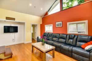 sala de estar con sofá de cuero negro y pared de color naranja en Massachusetts Vacation Rental 5 Mi to Fall River, en Somerset