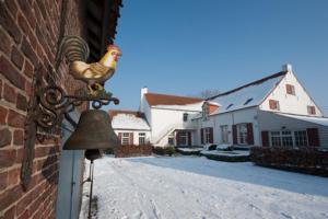 a chicken statue on the side of a building with a bell at B&B Hullebrug in Heist-op-den-Berg
