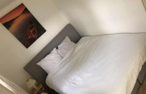 een bed met witte lakens en kussens in een kamer bij Sari in Steendam