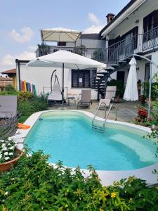 a swimming pool with an umbrella and a house at A Vijeta in Castiglione Falletto