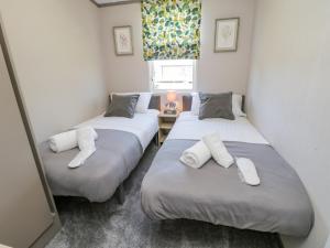 two twin beds in a room with a window at Jean's Place in Ganton