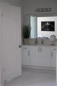 a white bathroom with a sink and a mirror at Luxury Vacation House in Miami’s Center! in Miami