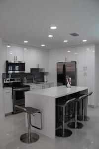 a white kitchen with a white counter and stools at Luxury Vacation House in Miami’s Center! in Miami