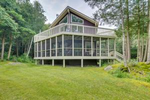 a large house with a large deck in the woods at Lakefront Otis Home with Stunning Views and Boats! in Otis