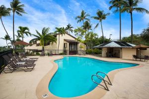 a swimming pool with chairs and palm trees at Country Club Villas 338 in Kailua-Kona