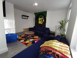 a living room with a blue couch and a painting at The Bob Marley 'One Love' Apartment, Relaxed Vibes in Liverpool