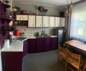 a kitchen with purple cabinets and a sink and a refrigerator at Domek nad morzem in Sopot