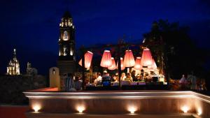 a group of people sitting at a bar with a clock tower at Concepción Hotel Boutique - Adults Only in San Miguel de Allende