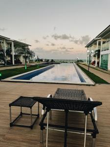 a table and chairs on a deck with a swimming pool at Bangalô duplex 602 - Riviera do Atlântico in Conde