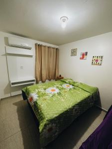 um quarto com uma cama verde com flores em Bangalô duplex 602 - Riviera do Atlântico em Conde