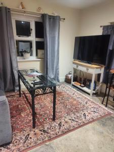 a living room with a table and a tv at The Dairy in Pershore