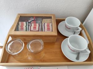 uma bandeja de madeira com duas xícaras, pires e livros em Guest House Adria em Primošten