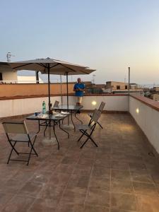 a man standing on a rooftop with tables and an umbrella at Porta Palermo Centro Sciacca in Sciacca