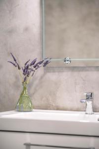 a vase with purple flowers sitting on top of a sink at Petrina Volia - Residence Anemos in Andros
