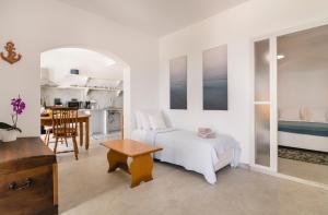 Dormitorio blanco con cama y mesa en Petrina Volia - Residence Anemos, en Ándros
