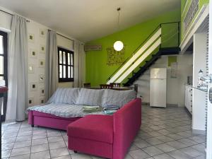 ein Wohnzimmer mit einem Sofa und einem rosa Stuhl in der Unterkunft Casa vacanze Artemide in Scario