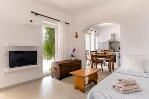 1 dormitorio con 2 camas y comedor con mesa en Petrina Volia - Residence Anemos, en Ándros