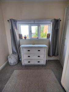 a white dresser in a room with a window at The Dairy in Pershore