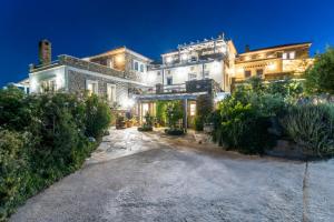 una gran mansión blanca con un patio por la noche en Petrina Volia - Residence Anemos, en Ándros