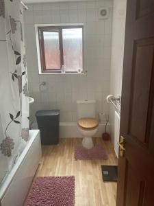 a bathroom with a toilet and a tub and a window at Spacious flat with free parking in Croydon in Croydon