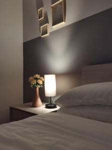 Dormitorio con cama, lámpara y flores en holy home, en Mestre