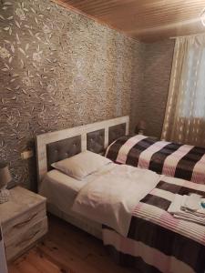 - une chambre avec 2 lits et un mur recouvert de papier peint dans l'établissement Melen, à Mestia