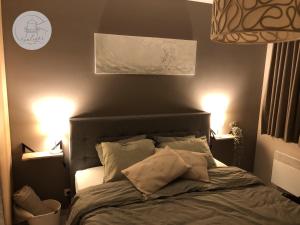 a bedroom with a bed with two lights on at Appartement Sealight in De Haan