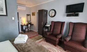 Kairos Guesthouse Orania في Orania: غرفة بسرير وكرسيين وساعة
