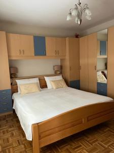 um quarto com uma cama grande com lençóis brancos e armários azuis em Apartment Adriana em Biograd na Moru