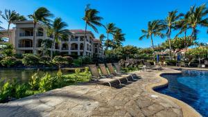 a resort with a pool and chairs and palm trees at The Shores at Waikoloa 117 in Waikoloa