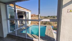 a house with a swimming pool seen through windows at Kairos Guesthouse Orania in Orania