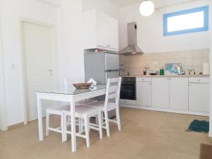 a white kitchen with a white table and chairs at Kostantis Vacation Home 1 in Ambelas
