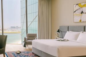 - une chambre avec un lit, une chaise et une grande fenêtre dans l'établissement Sonder at JBR The Walk, à Dubaï