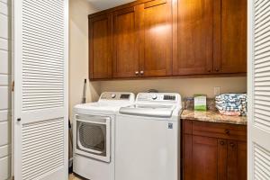 a kitchen with a washer and dryer and wooden cabinets at Holua Kai 37 in Kailua-Kona