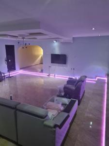 sala de estar con sofás morados y TV en Chic 4 Bed bungalow Oluyole Akala express Ibadan, en Ibadán