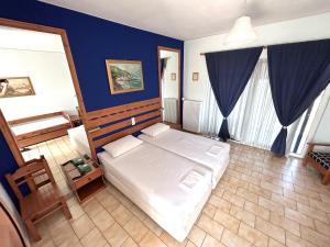 a bedroom with a bed and a blue wall at Bay Holiday Hotel & Spa in Karavómilos