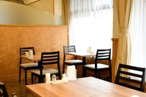 um restaurante com mesas e cadeiras de madeira e uma janela em Marroad inn omiya em Saitama
