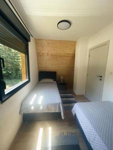 een kleine slaapkamer met 2 bedden en een raam bij Zminica Lake House in Žabljak