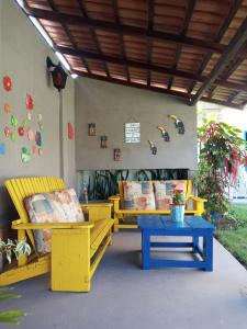 une terrasse avec des chaises jaunes et une table bleue dans l'établissement Recanto do Hibisco, à Prado
