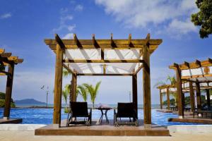 un pabellón de madera con sillas y una mesa junto al agua en 21P Penthouse 2 balconies Oceanview Panama, en ArraijÃ¡n