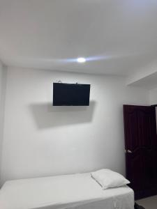 Habitación con cama y TV en la pared. en Hotel Casa Evan, en Mompox
