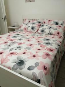 a bed with pink and gray flowers on it at B&B COLLE TARIGNI in Manoppello