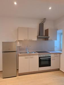 a kitchen with white cabinets and a stainless steel refrigerator at Flower in Poljica +3 photos