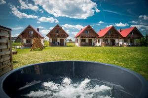 a pool of water in front of some houses at KALINOWY SAD DOMKI z JACUZZI i SAUNĄ in Mikołajki