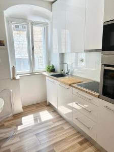 a kitchen with white cabinets and a wooden floor at Luxury apartment Aura in Supetar