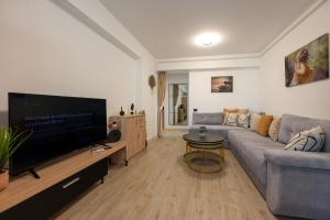 uma sala de estar com um sofá e uma televisão de ecrã plano em Crystal Beach 228 - Infinity Pool & Spa Resort em Mamaia Nord – Năvodari