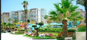 a park with palm trees and flowers and a building at Wunderschönes Apartment im Palm Lake Resort - S+2 très haut standing für bis zu 5 Personen in Monastir