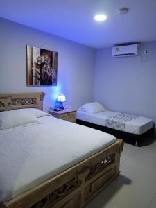 two beds in a room with purple lighting at Hotel Prado 53 in Barranquilla