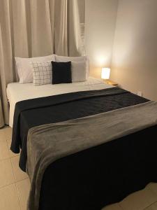 a bed with a black blanket and white pillows at Prime Hotel in Arcos