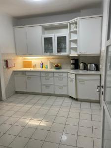 a kitchen with white cabinets and a tiled floor at Pension zum Landhaus in Drewitz